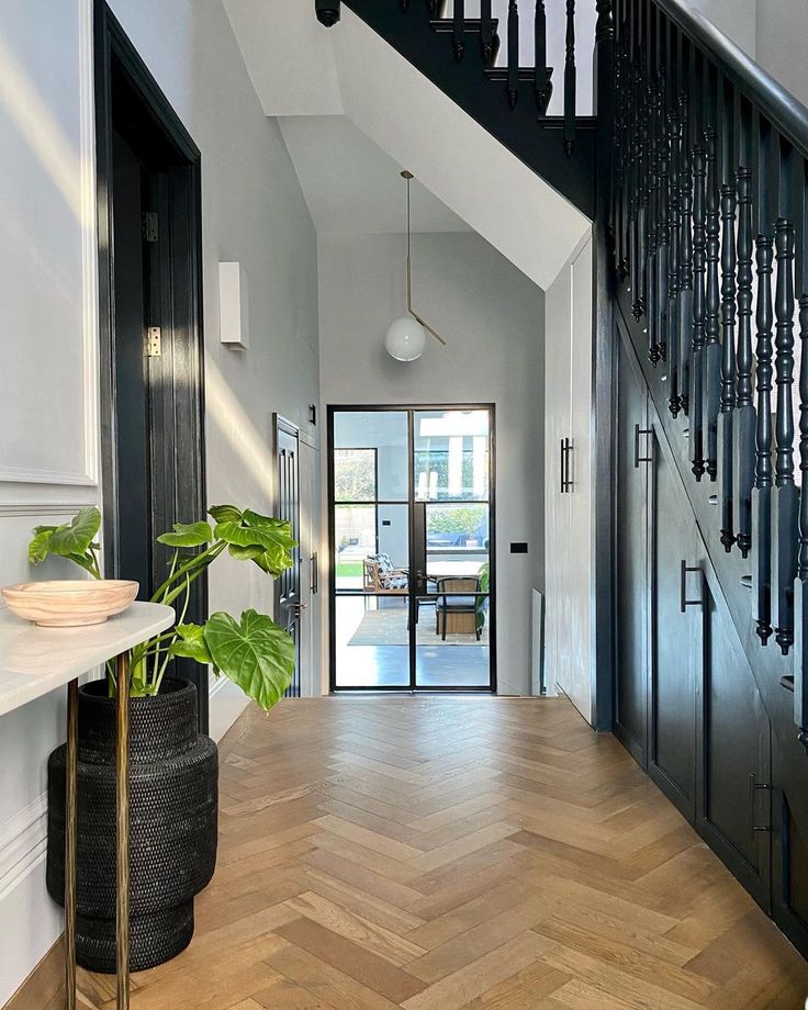 a foyer with wooden floors and black iron banisters on the wall, along with a potted plant