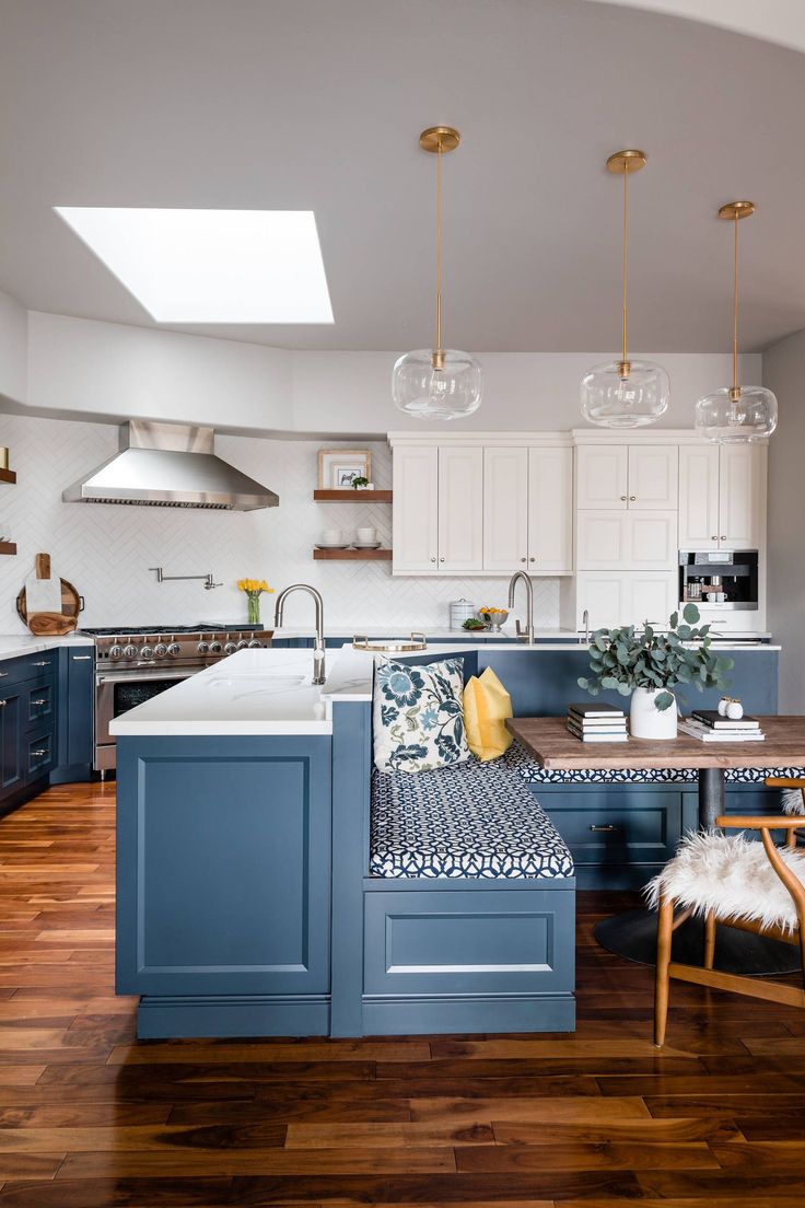 a kitchen with blue cabinets and white counter tops, wooden flooring and an island in the middle