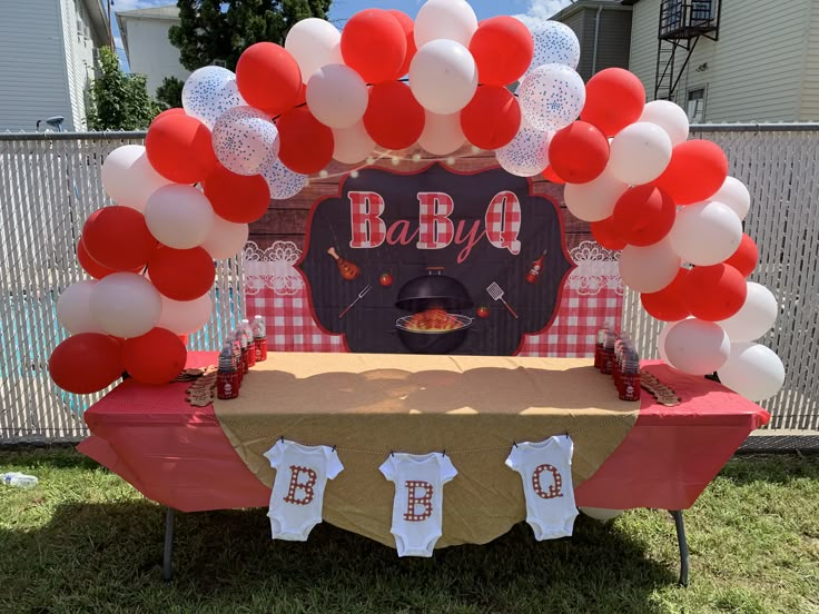 a bbq baby shower with balloons and cake on the table in front of it