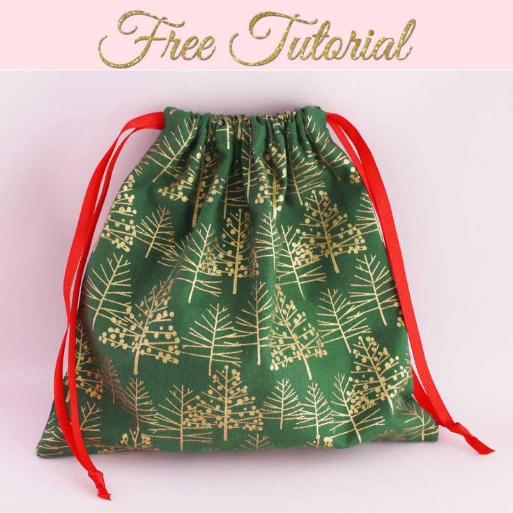 a green drawsack bag with gold trees on it and red ribbon around the bottom