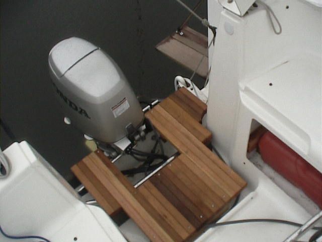 a motor boat with a small wooden table on the front deck and an outboard motor behind it