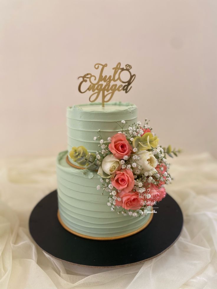 a blue cake with flowers on top sitting on a black plate next to a white table cloth