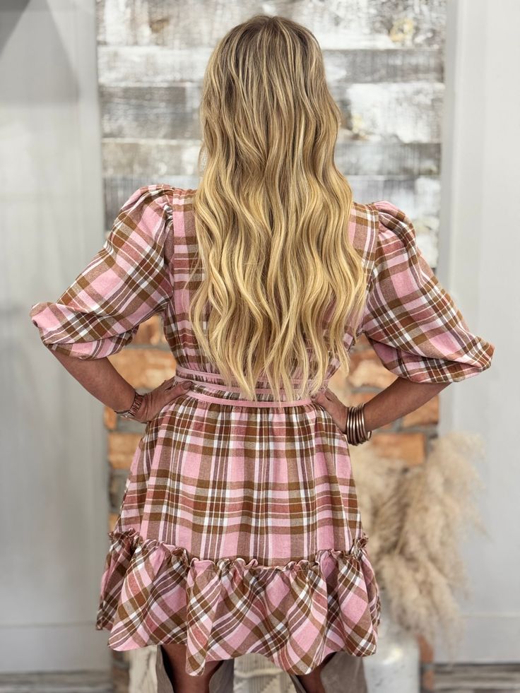 the back of a woman wearing a pink plaid dress with ruffled sleeves and long legs