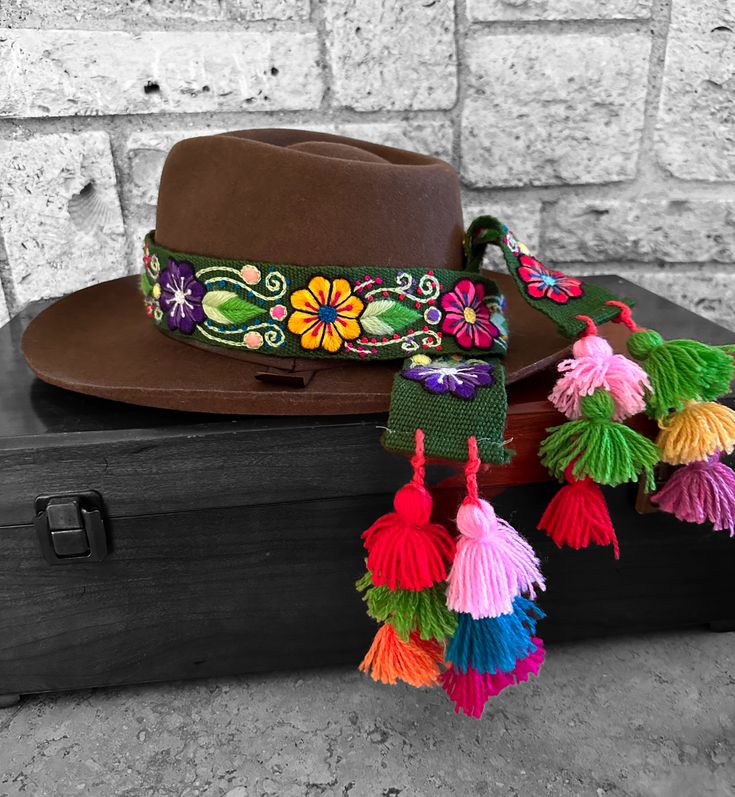 Our Western style hat bands are unique, hand embroidered, adjustable and can be mixed and matched with multiple hats. Finished with beautiful colorful pompons, length is approximately 38" and width 2". They are hand made by Artisans of the Andes in Peru. Each one is carefully crafted and made with LOVE! GreenLength 38"Width 2" Artisan Adjustable Mini Hats For Festivals, Handmade Mini Hats For Festivals, Bohemian Multicolor Mini Hats For Festival, Artisan Handmade Adjustable Mini Hats, Bohemian Brown Mini Hat For Festivals, Bohemian Adjustable Multicolor Mini Hats, Adjustable Bohemian Multicolor Mini Hats, Handmade Bohemian Mini Hats, Handmade Bohemian Mini Cap