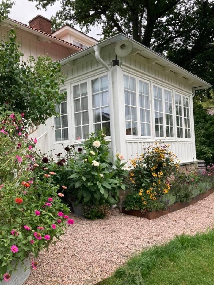 a small white house surrounded by flowers and trees