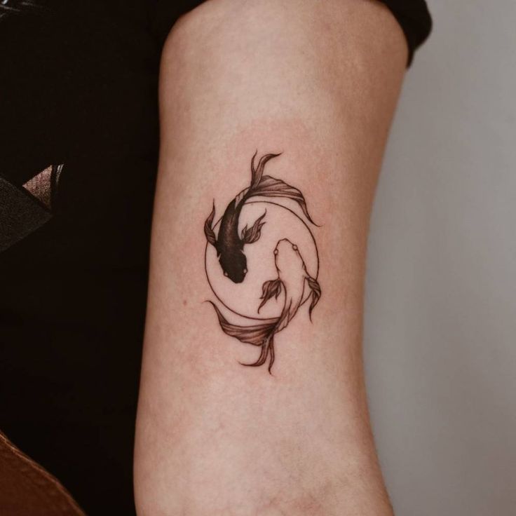 a woman's arm with a black and white koi fish tattoo on it