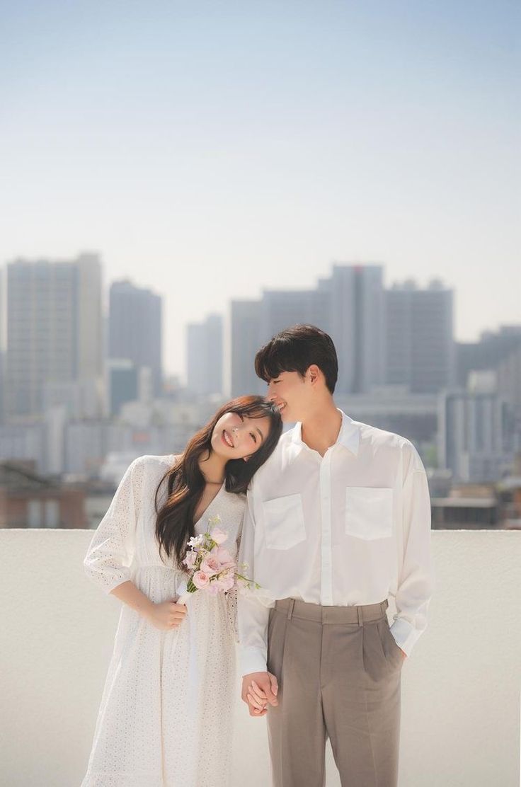 a man and woman standing next to each other in front of a cityscape