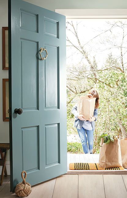 a woman holding a paper bag in front of an open door