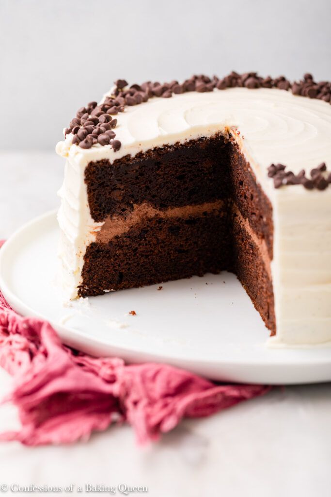 a chocolate cake with white frosting and chocolate chips on the top is cut in half