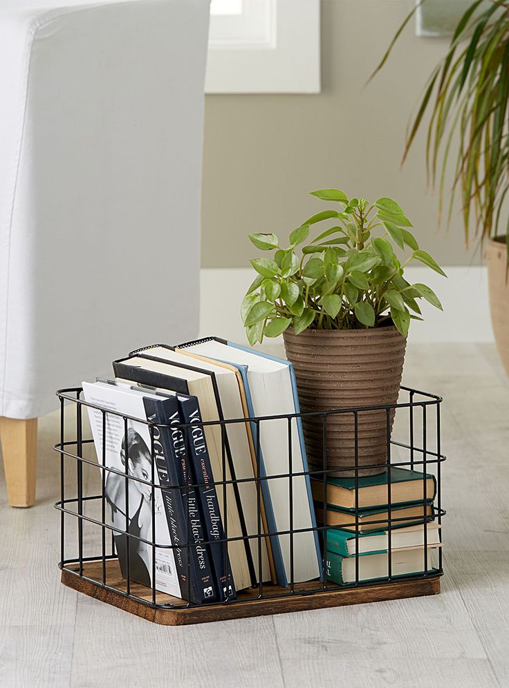 a metal basket with books and plants in it