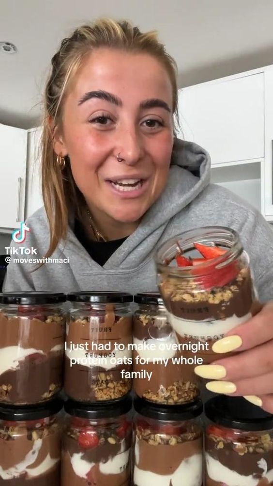 a woman holding a jar filled with desserts