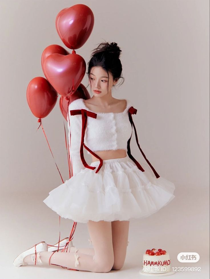 a woman in a white dress holding red balloons