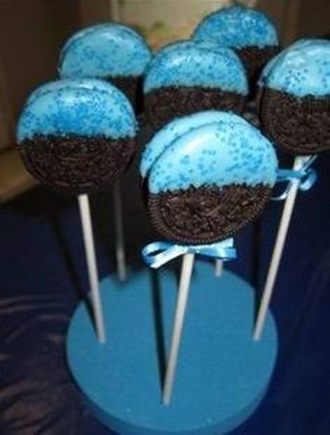 chocolate cake pops with blue frosting and brown sprinkles on top are arranged in a cupcake holder