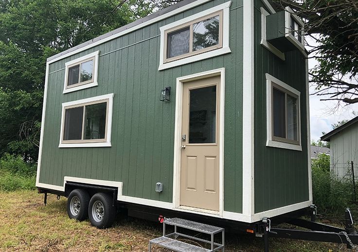 a green tiny house sitting on top of a trailer