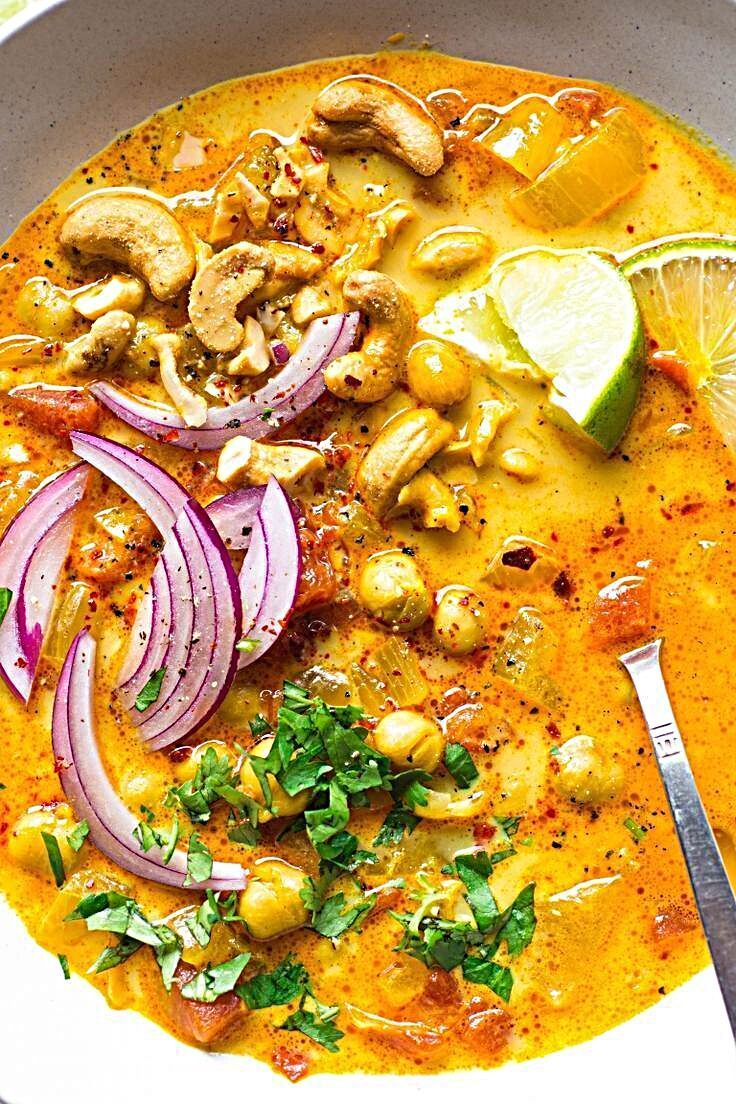 a white bowl filled with food and garnished with cilantro, onions, mushrooms, and lime