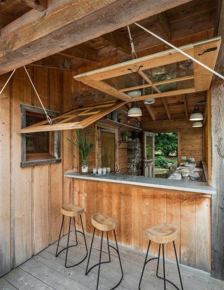 an outdoor bar with three stools on the floor and wood paneling around it