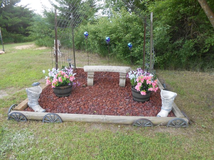 a garden area with flowers and plants in the center, surrounded by wooden wagon wheels