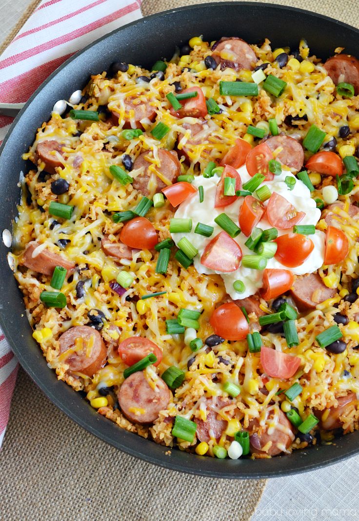 a skillet filled with rice and vegetables on top of a striped table cloth next to a red and white towel