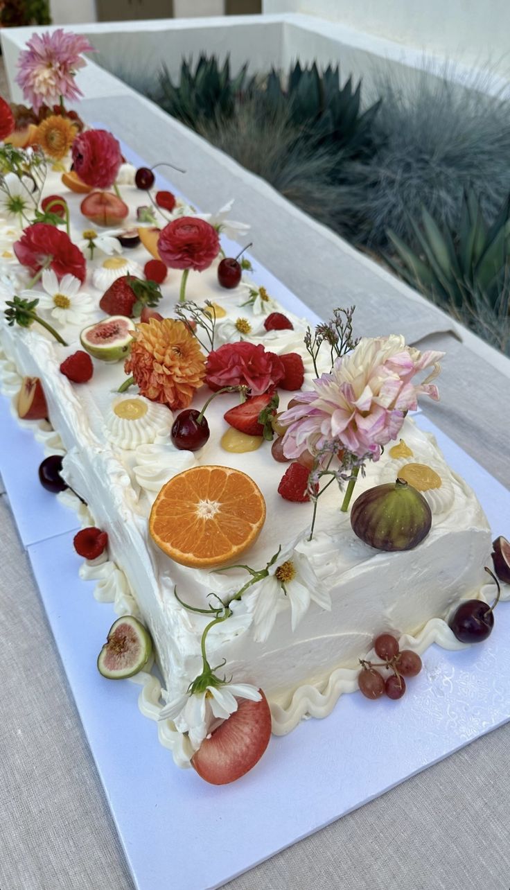 a white cake with fruit and flowers on it