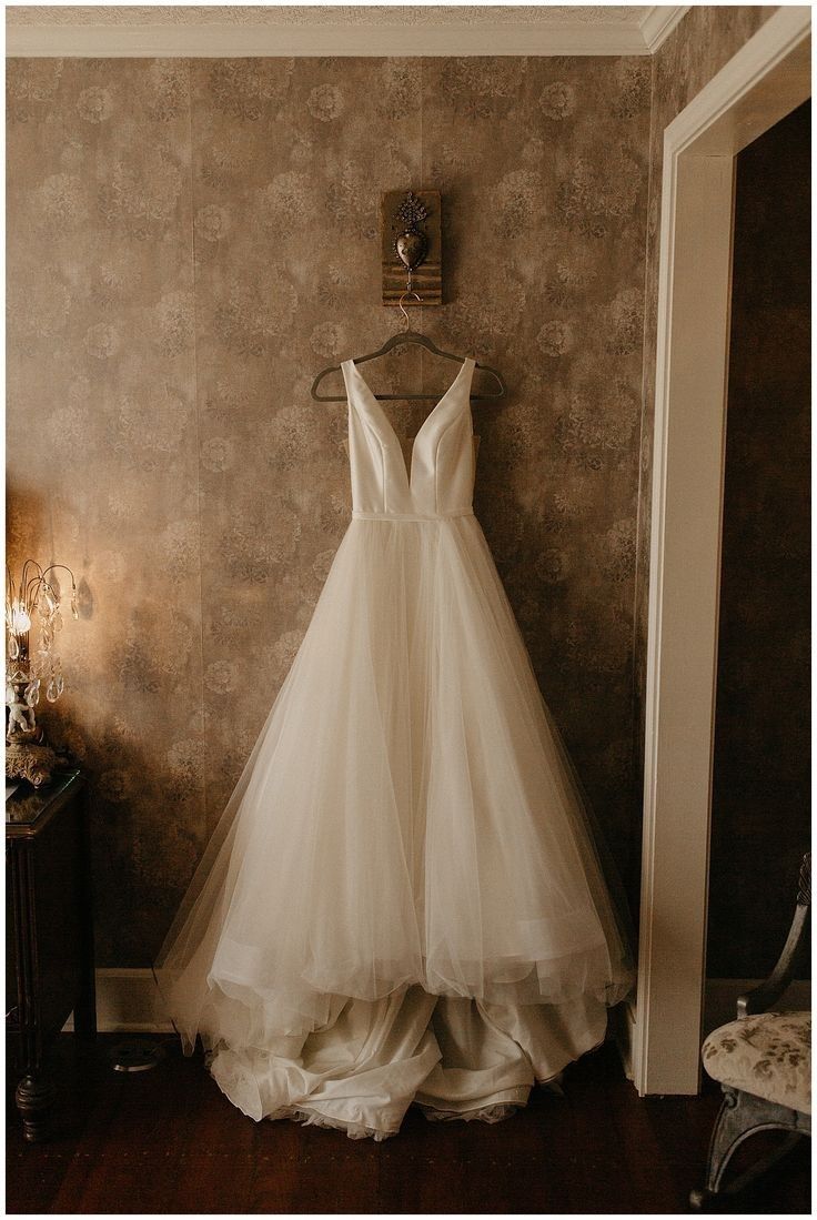 a wedding dress hanging up against a wall