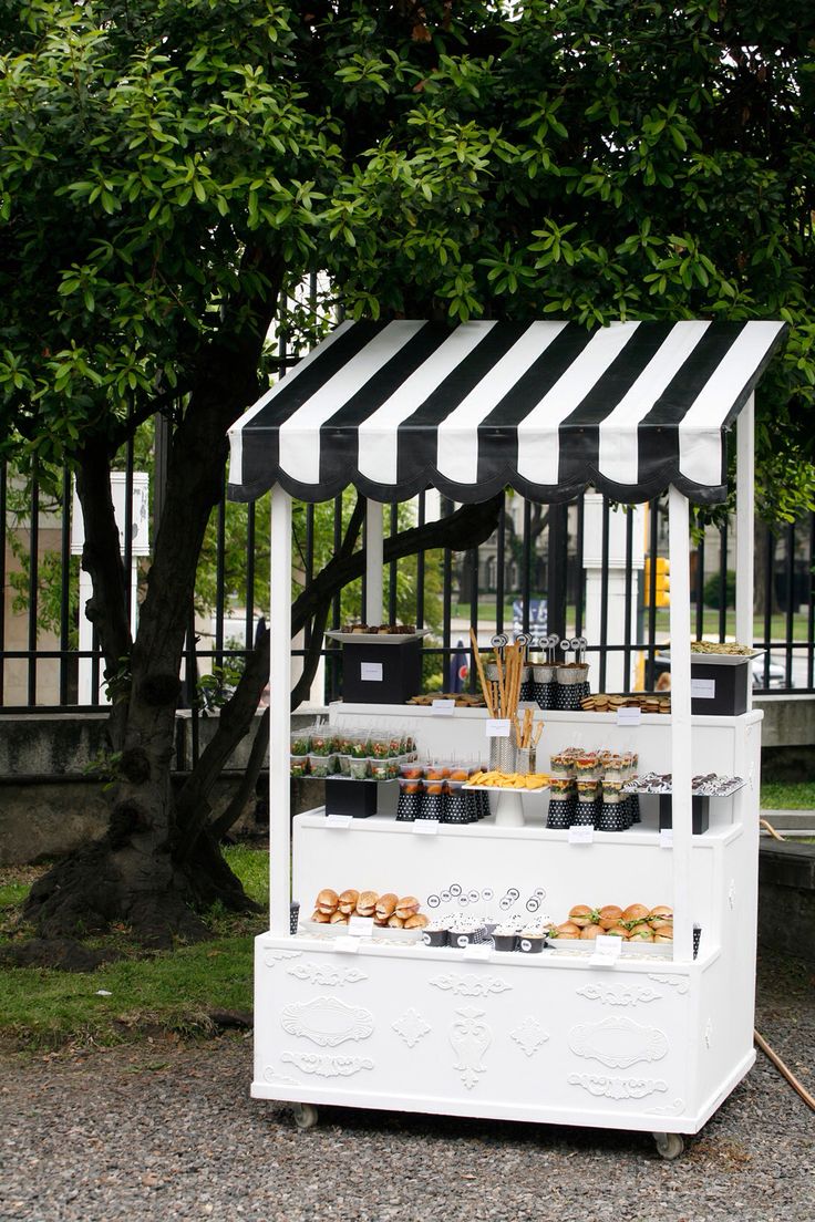 a white and black striped awning on top of a stand with donuts in it