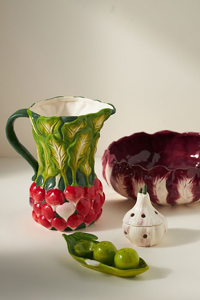 three vases and two green peppers on a white surface with one being red, the other is green