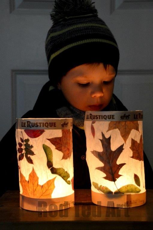 a young boy sitting at a table looking at two paper bags with leaves on them