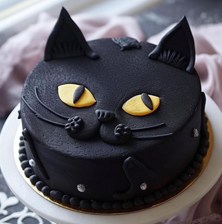 a black cat cake with yellow eyes on a plate