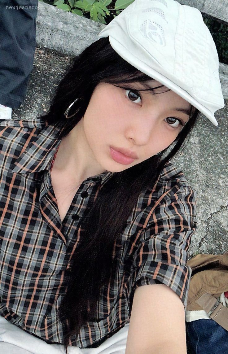 a woman sitting on the ground wearing a white hat and looking up at the camera