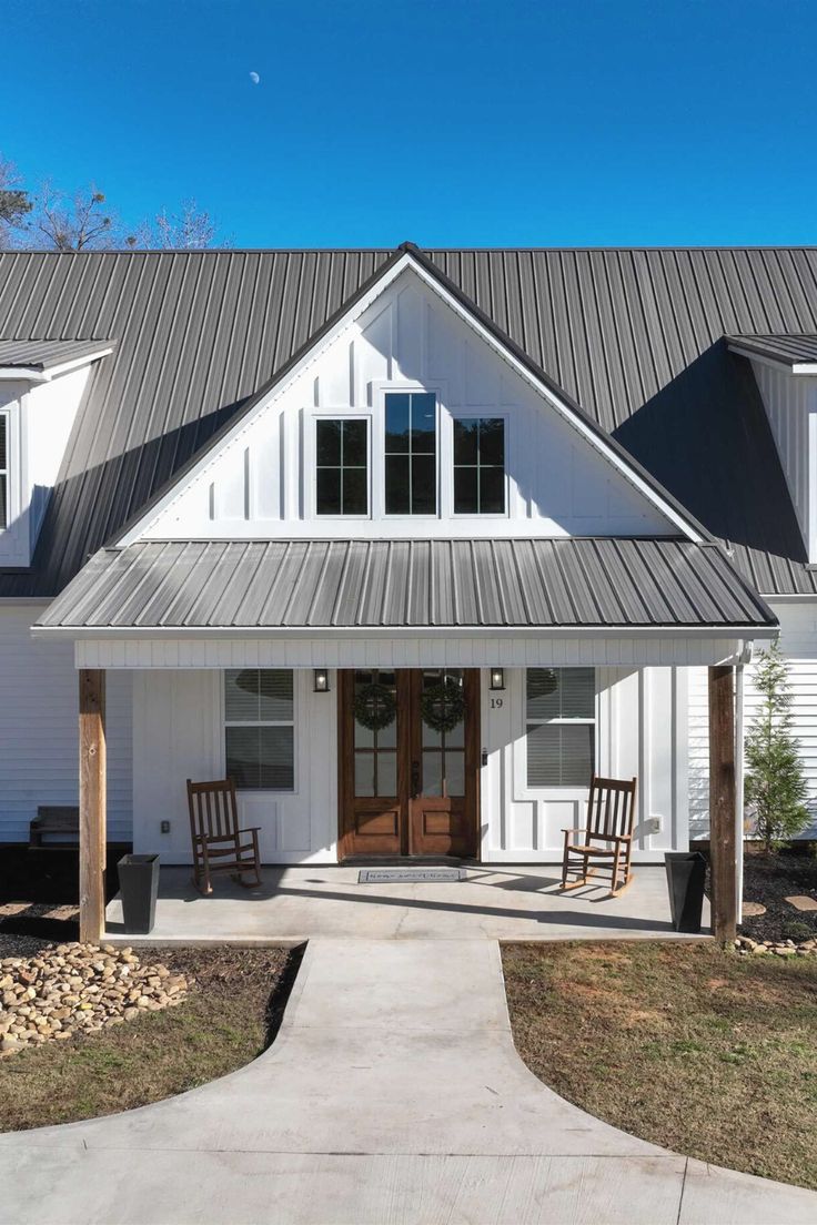 a white house with two rocking chairs on the front porch