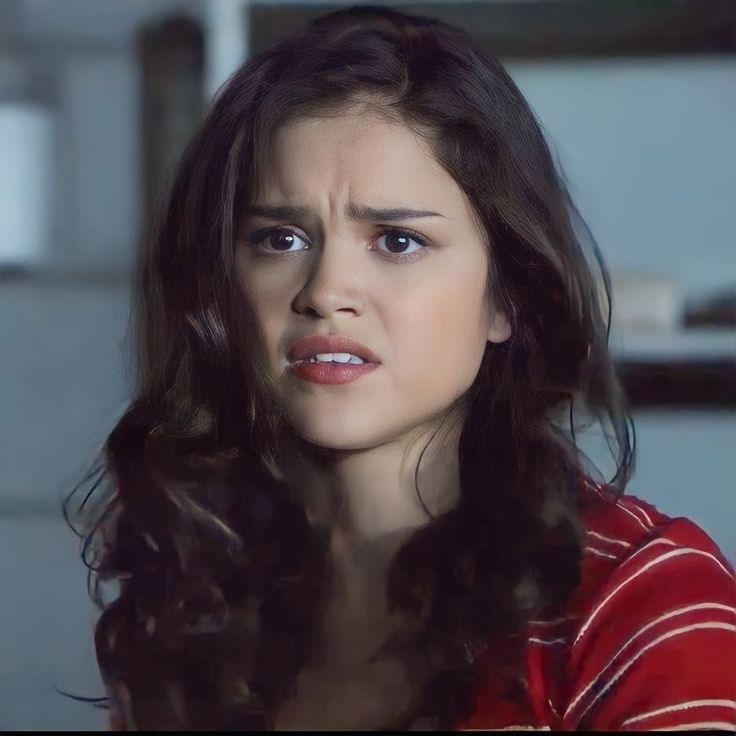 a woman with long dark hair wearing a red and white striped shirt looking at the camera