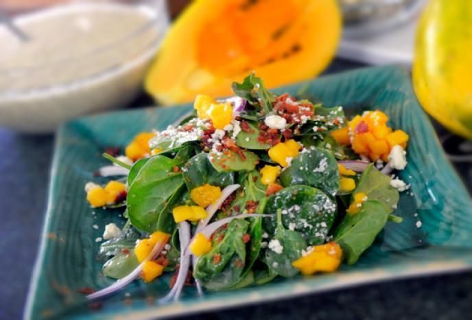 a green plate topped with salad next to oranges