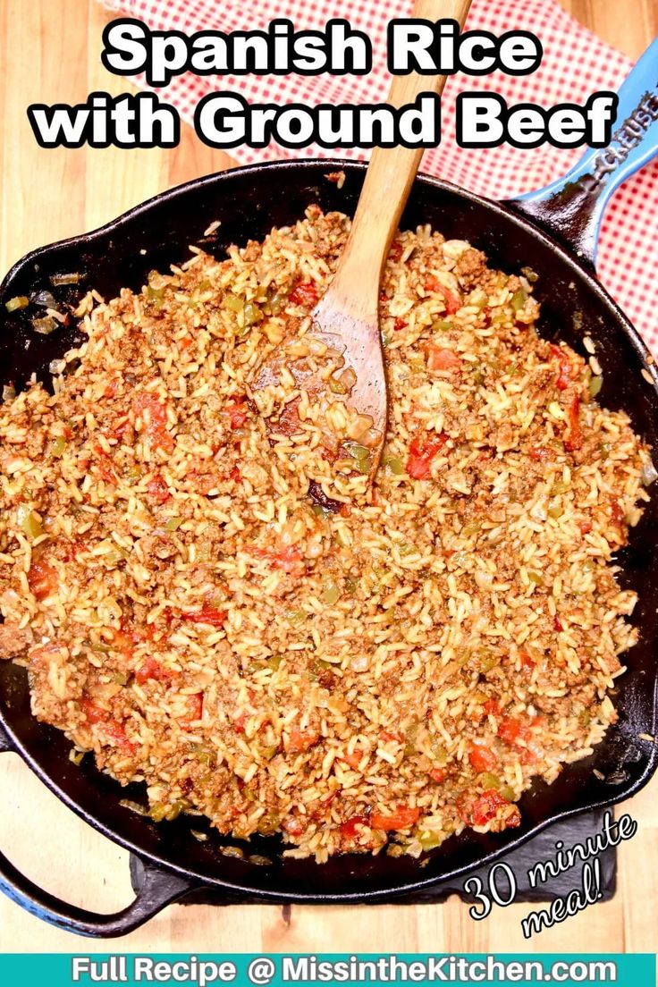 a skillet filled with rice and vegetables on top of a wooden table next to a red checkered napkin