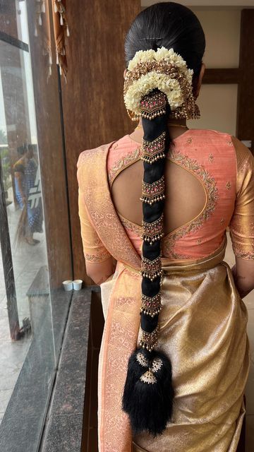 a woman in an orange and gold sari with a long braid on her head