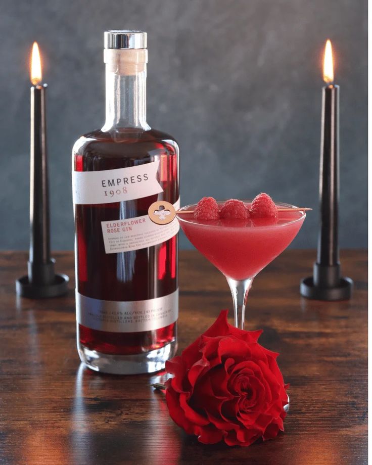 a bottle of liquor next to a glass filled with liquid and a rose on the table