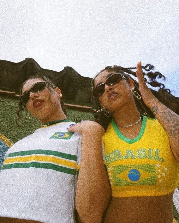 two young women standing next to each other in front of a building with mountains behind them