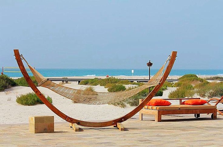 two hammock chairs sitting on top of a sandy beach