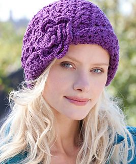 a woman with blonde hair wearing a purple knitted hat and looking at the camera