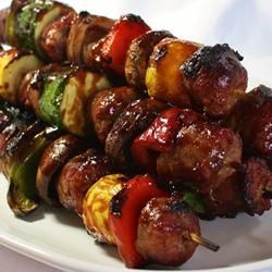 several skewers of meat and vegetables on a white plate