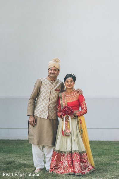 a man and woman standing next to each other in front of a white wall with grass