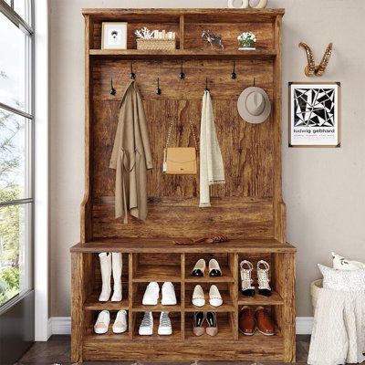 an old wooden coat rack with shoes and coats hanging on it's sides next to a window