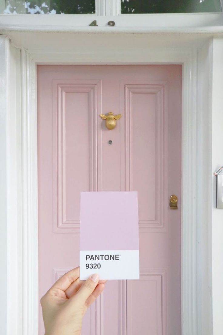 a person holding up a pink door with the name pantone on it