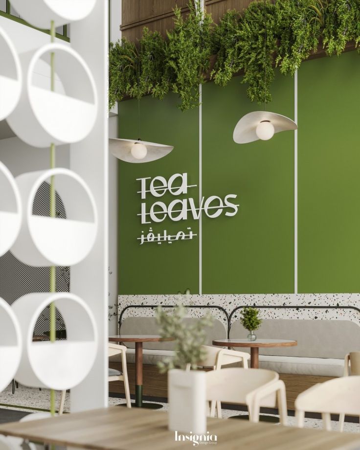 the interior of a restaurant with green walls and hanging plants on the wall, along with wooden tables and white chairs