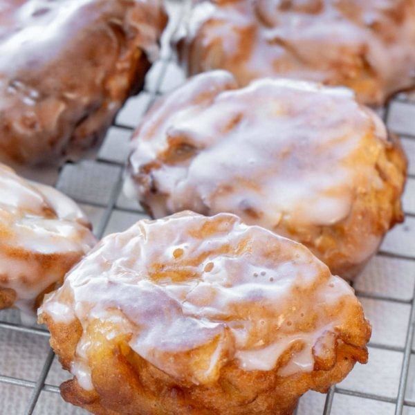 several glazed donuts sitting on a cooling rack with icing drizzled over them