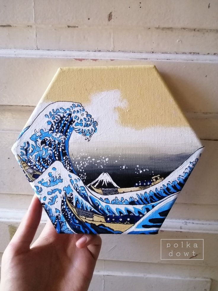 someone is holding up an origami box with a painting of the great wave on it