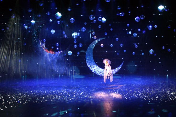 a woman standing on top of a stage in front of a moon and stars background