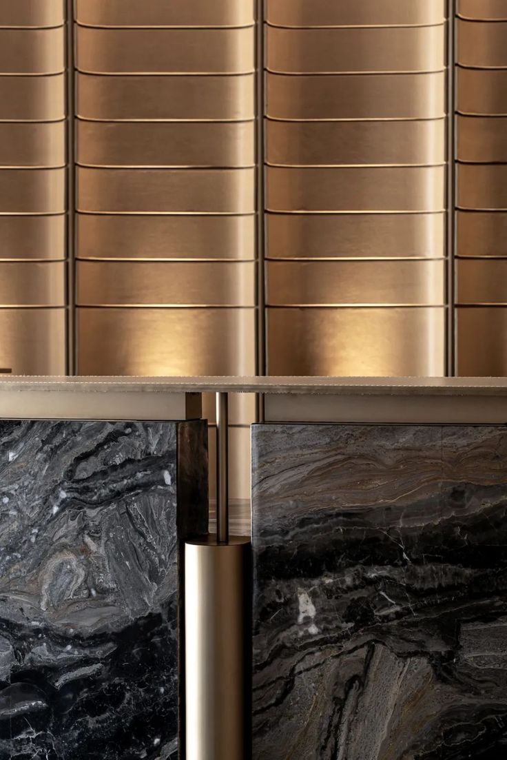 two black and gold marble counter tops in front of a metal wall with vertical blinds