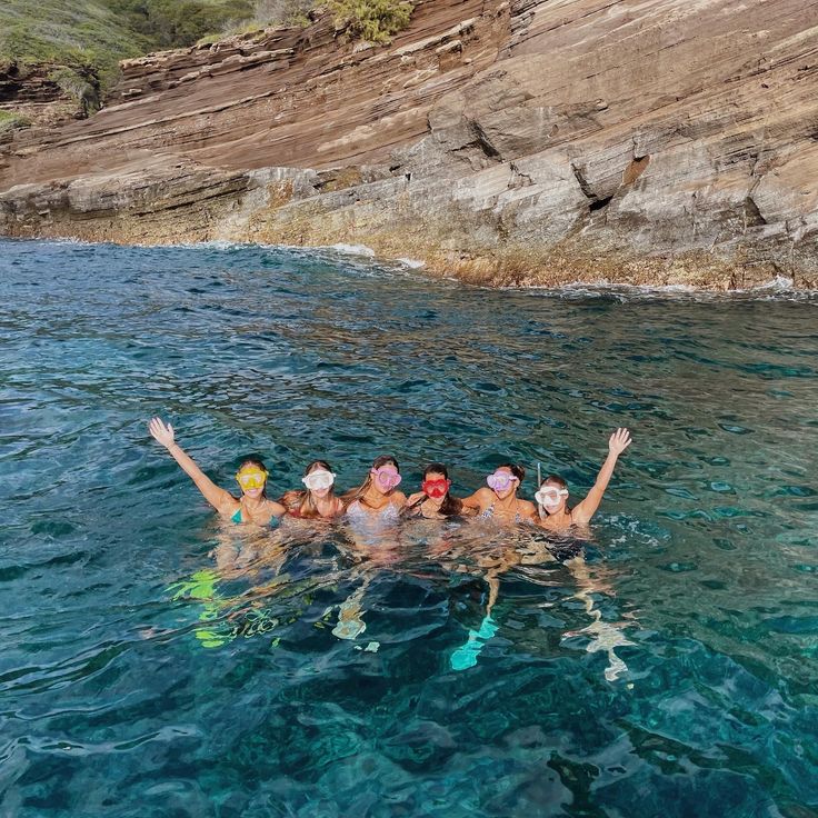 four people in the water with their arms up