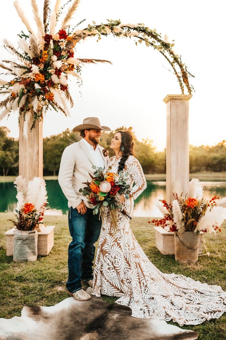 a man and woman standing under an arch with flowers