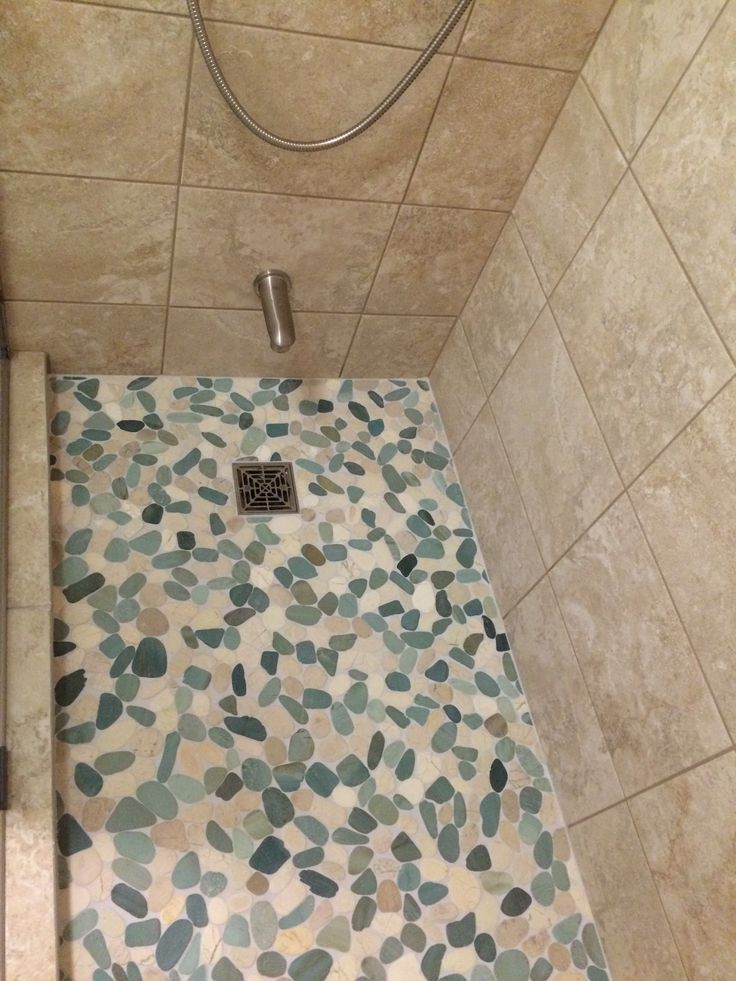 a tiled shower stall in a bathroom with blue and green mosaic tiles on the floor